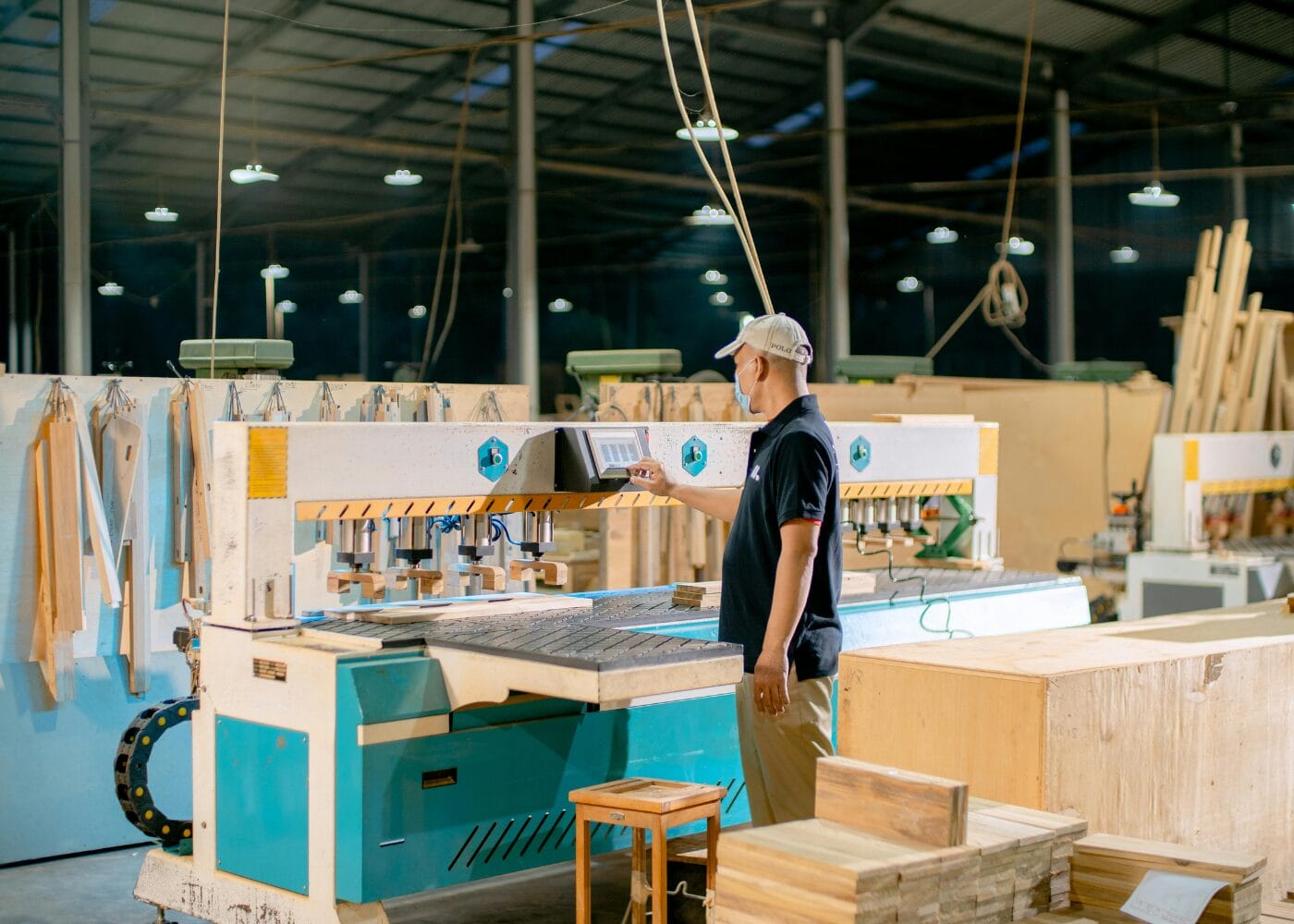 Factory worker operating a CNC woodworking machine, precision cutting lumber.