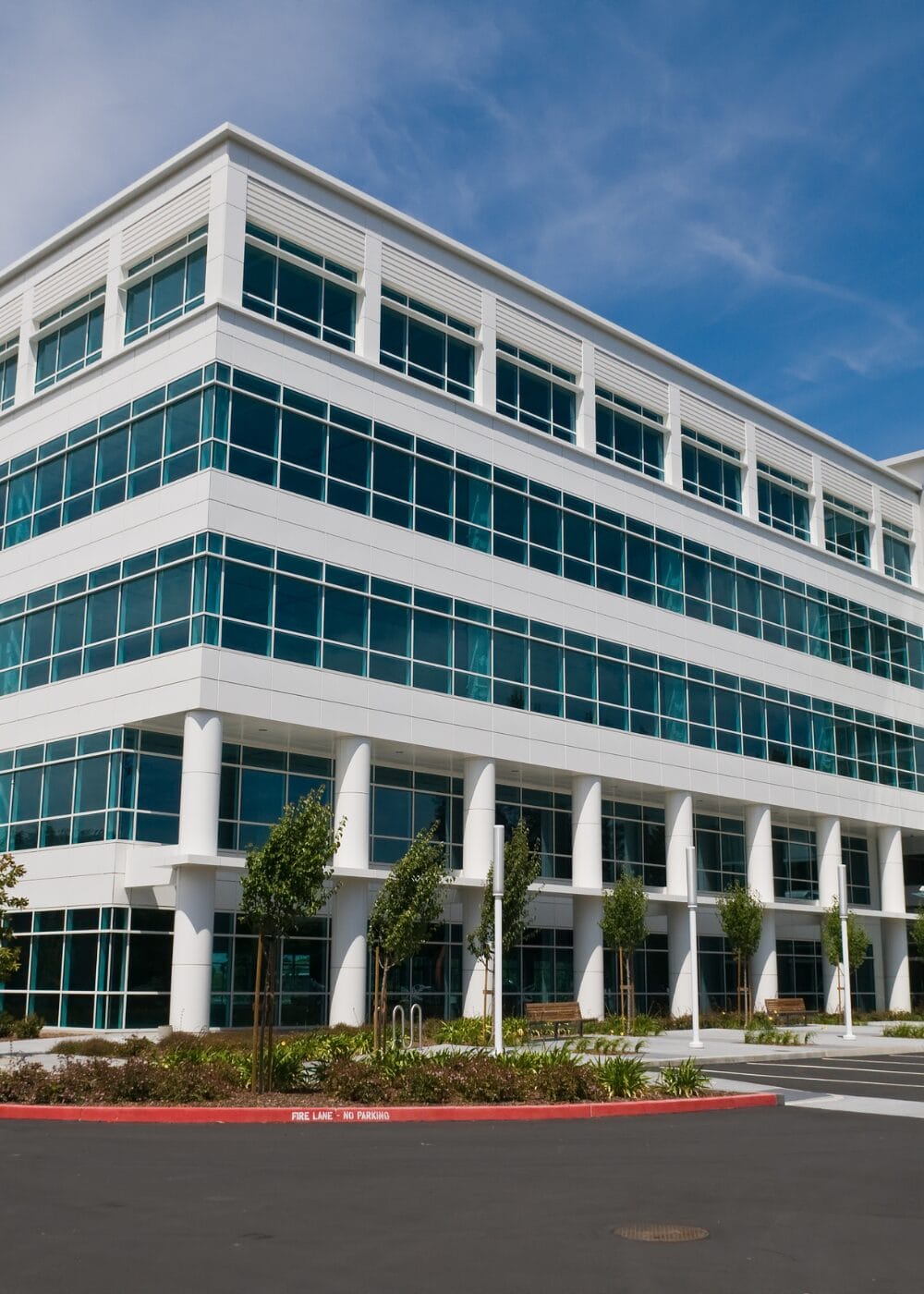 Modern white office building with large windows and landscaping