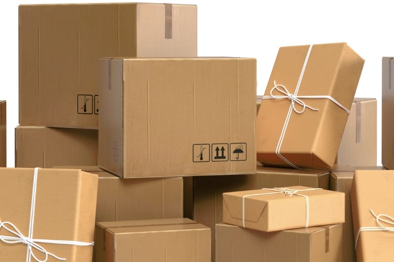Stack of cardboard boxes, some tied with string, ready for shipping.